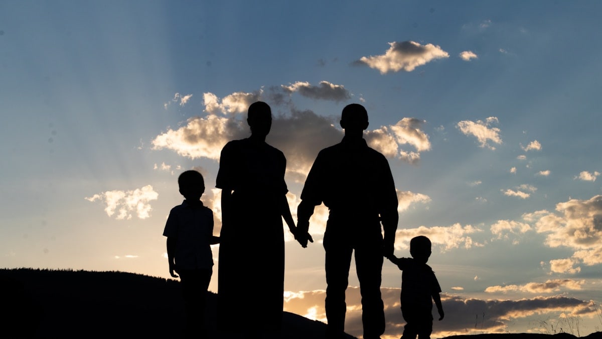 a group of people standing on a hill looking at the sunset